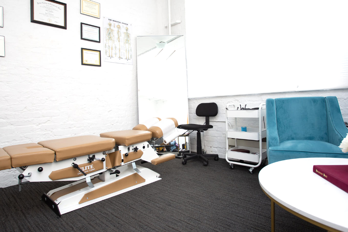 The Alem Integrated Health treatment room in San Francisco — chiropractic table, framed credentials, and a calm seating area